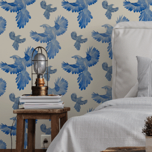 A zoomed-in azure blue birds in flight peel and stick wallpaper behind rustic wooden side table and soft grey bedding in cozy bedroom