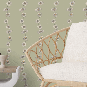 Zoomed-in of Ditzy Daisy Chain peel and stick wallpaper in taupe and ivory floral garlands on a soft sage green background behind a rattan chair with cream cushion
