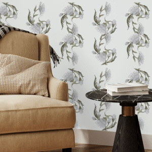 Flowery Chalk wallpaper in a cozy room setting with neutral armchair, mid-century wood sideboard, and light floral pattern on grey wall