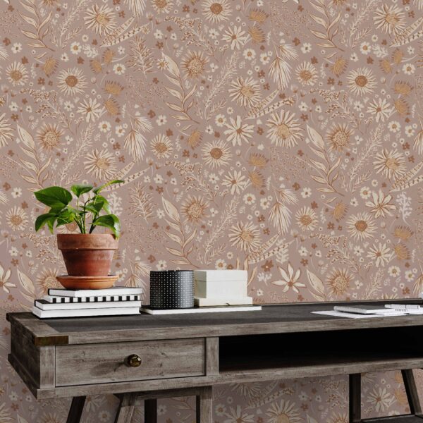 A zoomed-in boho floral wallpaper in blush pink and gold behind a rustic wood desk and antique chair in a cozy home office