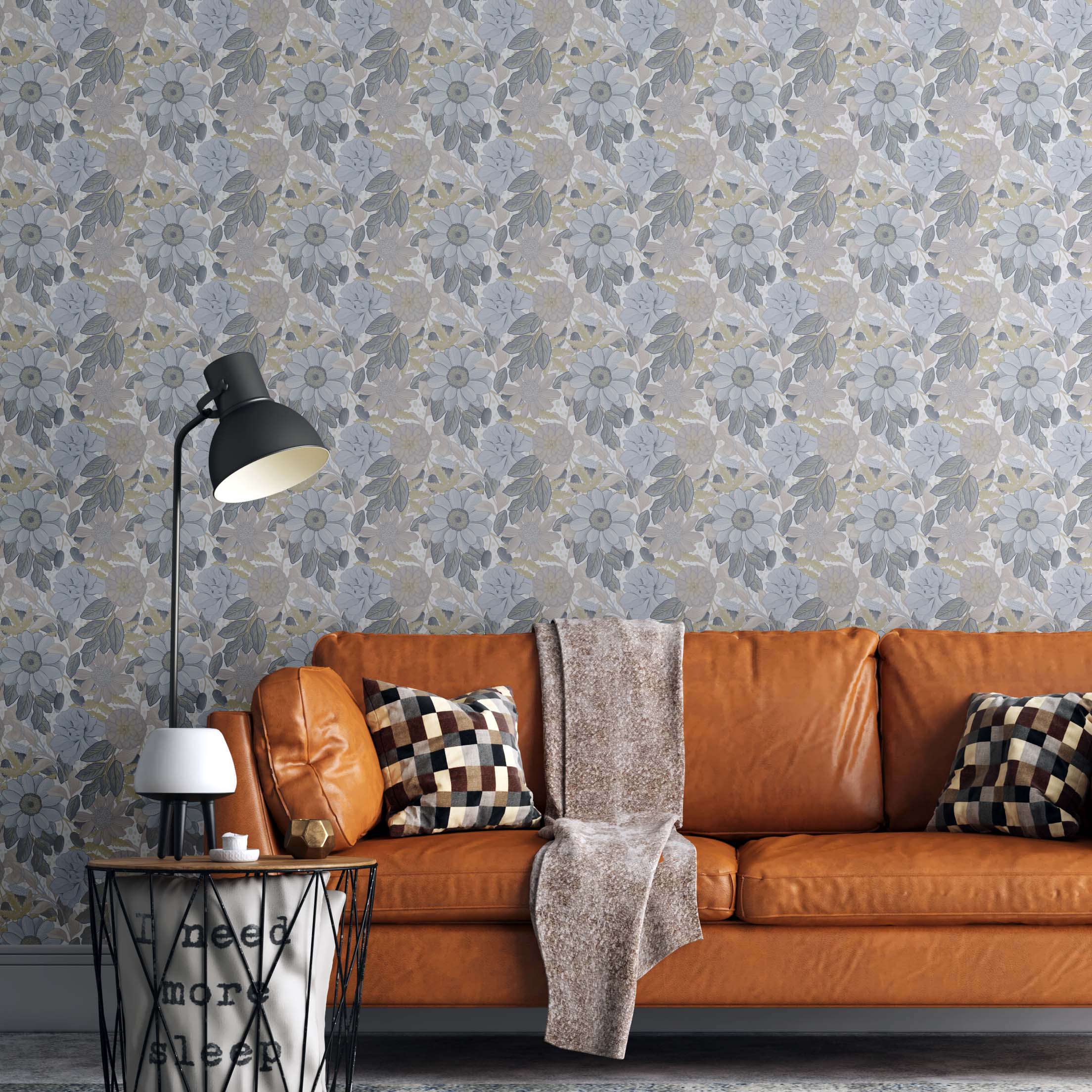 Garden Air Wallpaper | Peel & Stick Wallpaper Online | Proudly Made in Canada A Botanical wallpaper with soft powder blue florals behind a tan leather sofa, checkered pillows, and cozy neutral decor in a warm living space