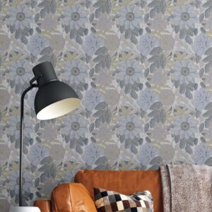 This is a zoomed-in Botanical wallpaper with soft powder blue florals behind a tan leather sofa, checkered pillows, and cozy neutral decor in a warm living space