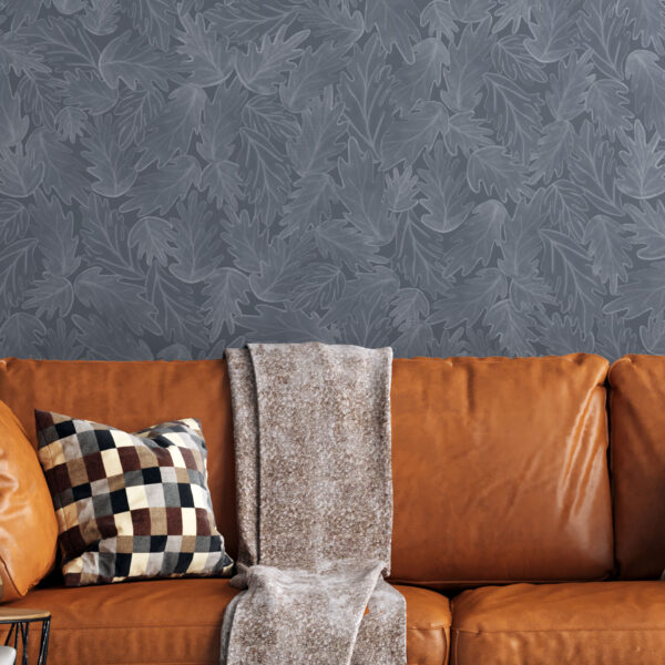 A zoomed-in Ruma Leaf Cluster wallpaper in steel blue tones behind a modern sofa in a contemporary living room.