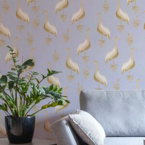 A zoomed-in heron-themed wallpaper in a serene lavender setting behind modern grey couch