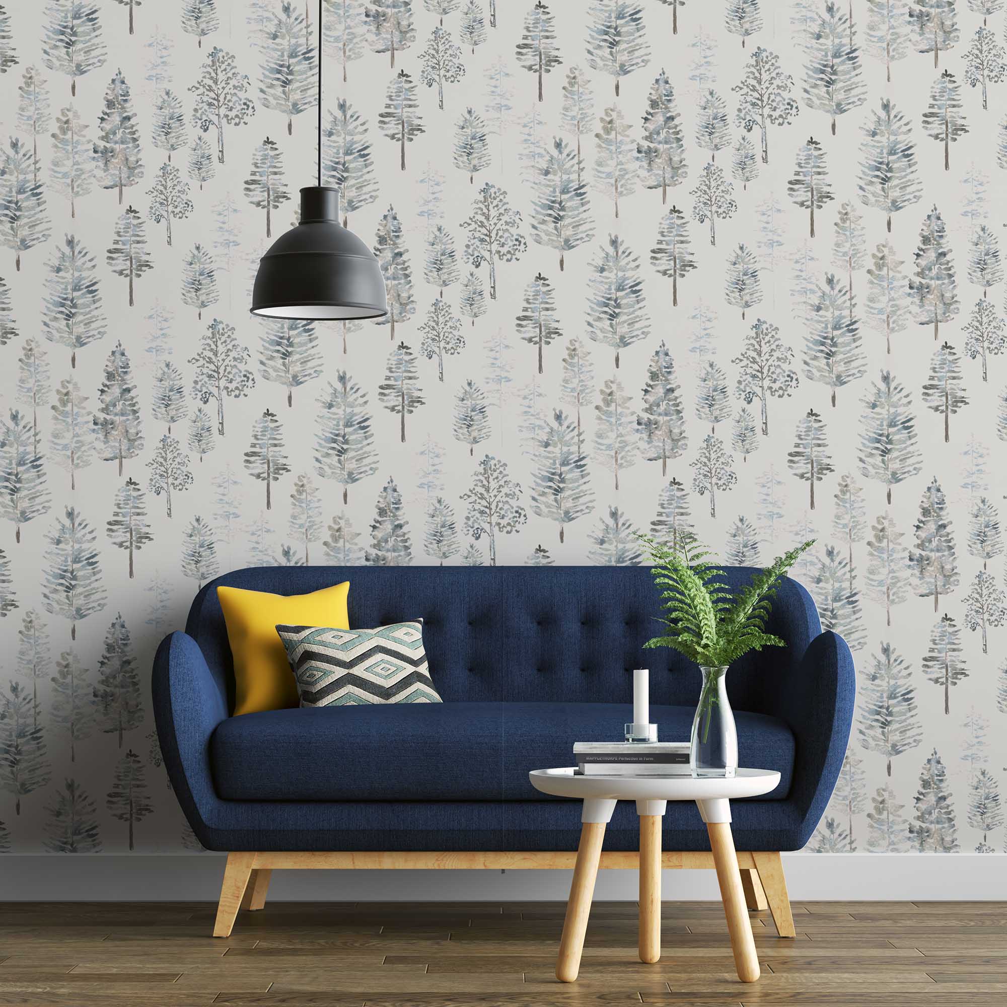 Whispering Pines Wallpaper | Peel & Stick Wallpaper Online | Proudly Made in Canada Whispering Pines peel and stick wallpaper in a living space with a navy blue couch and potted fern, showcasing soft watercolor pine trees in cool neutral tones