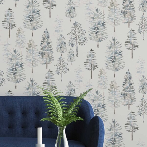 Whispering Pines peel and stick wallpaper in a living space with a navy blue couch and potted fern, showcasing soft watercolor pine trees in cool neutral tones