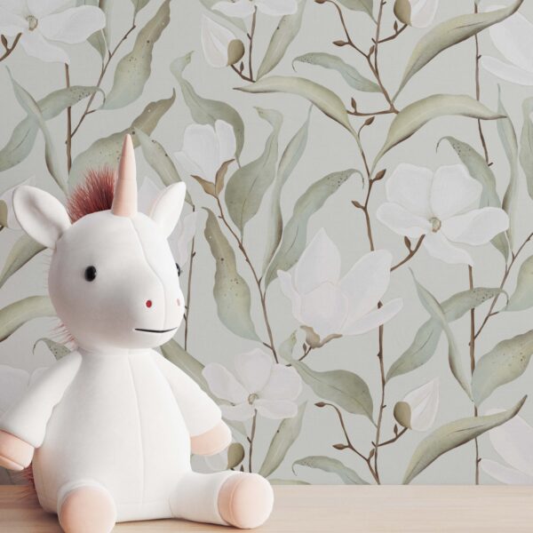 A zoomed-in soft white magnolia floral wallpaper in modern nursery setting with unicorn plush toy