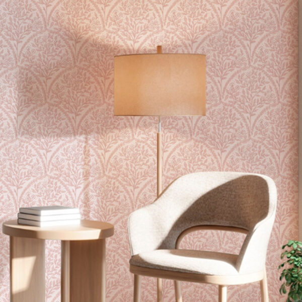 a zoomed-in of a soft pink scalloped floral wallpaper in a modern reading nook with a curved chair, wooden lamp, and side table.