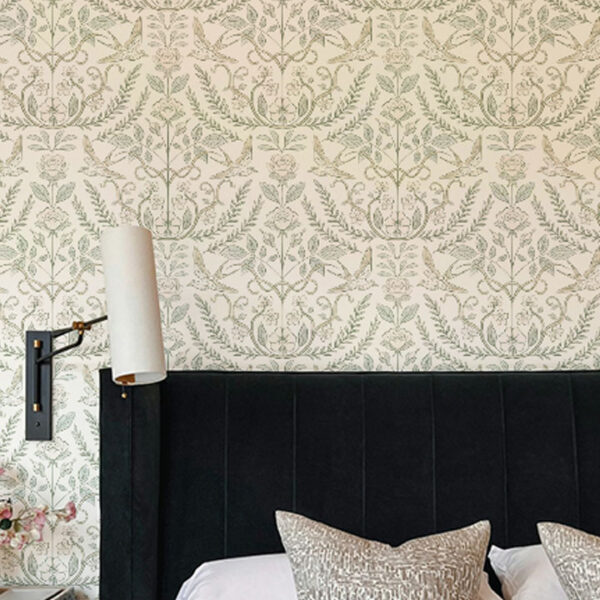 A zoomed-in of intricate green floral vines and birds on cream heirloom wallpaper