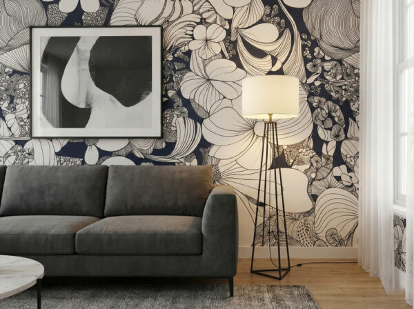 zoomed-in of Noir Botanical wallpaper with large hand-drawn floral outlines in black, ivory, and grey, styled with a charcoal sectional sofa, abstract wall art, and soft neutral decor.