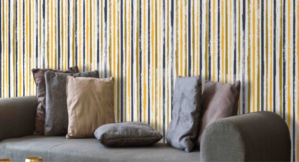 A beautiful Wholegrain Mustard Gouache Stripes wallpaper behind a sofa