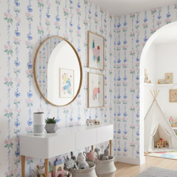 Light-filled playroom styled with pastel ribbon and rose wallpaper, white storage console, round mirror, and soft toy baskets.