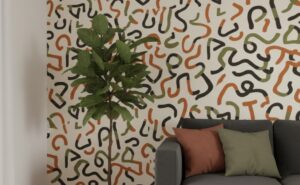 A zoomed-in of an abstract squiggle wallpaper with organic black, green, and terracotta lines paired with neutral seating and indoor plants.