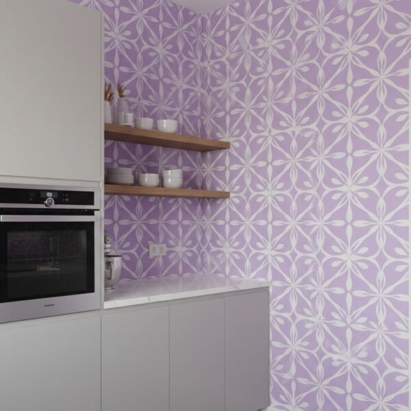 Lilac geometric petal wallpaper on a kitchen wall with built-in oven, floating shelves, and minimalist white finishes