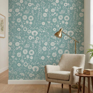 Teal folk floral wallpaper with white botanical illustrations styled in a cozy reading nook with a beige armchair, brass floor lamp, wooden side table, and light wood flooring.