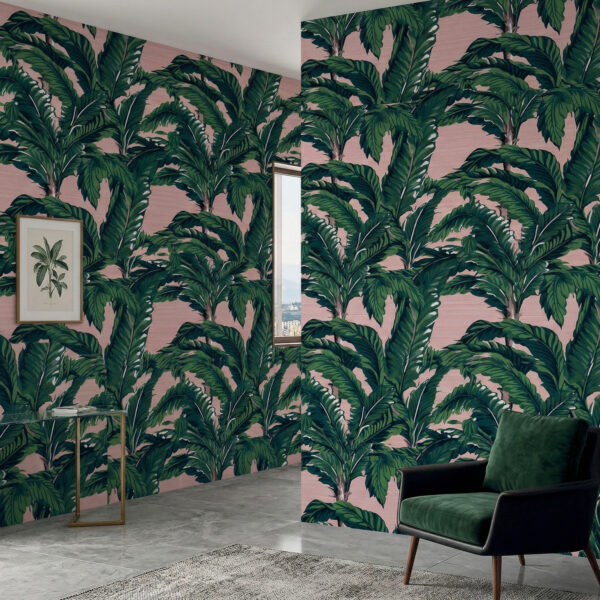 Blush banana leaf wallpaper installed in a modern corner space with framed botanical art and green velvet armchair.