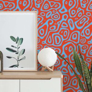 Zoomed-in groovy Baby wallpaper styled behind a cabinet with framed art and houseplants.