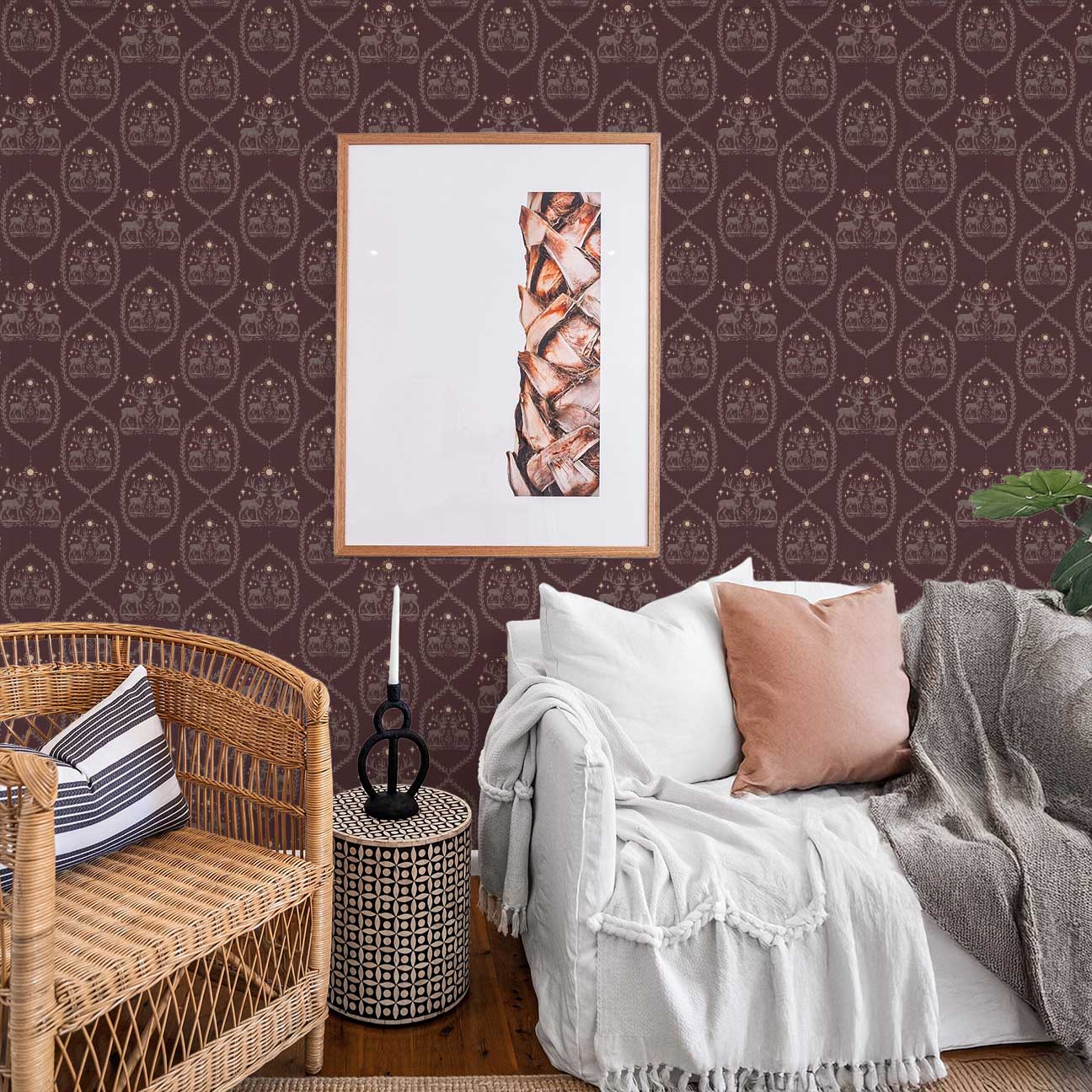 Winterfell Wallpaper in Plum | Peel & Stick Wallpaper Online | Proudly Made in Canada Winterfell Wallpaper in Plum installed behind a neutral sofa with rustic decor and repeating deer and crest pattern