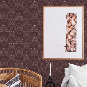 Winterfell Wallpaper in Plum styled in a cozy living room with wicker chair and detailed stag motif on deep burgundy background