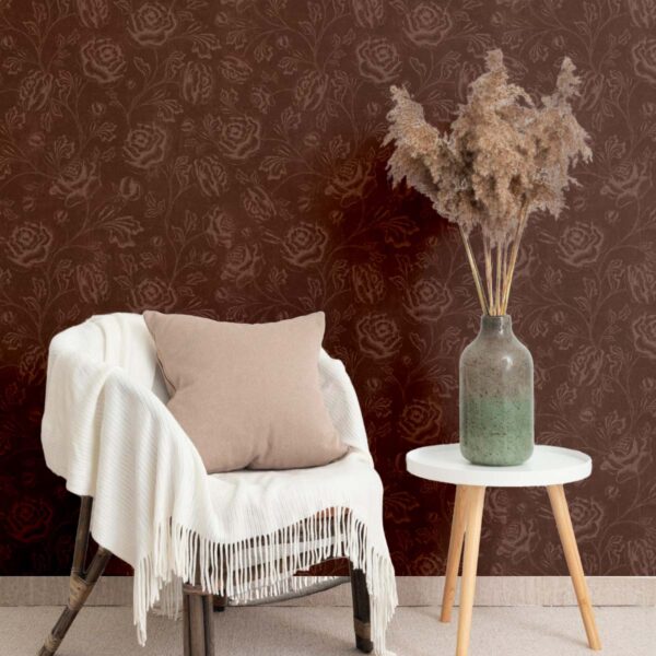 Magdalene Roses Toile wallpaper in a cozy corner setting with beige cushion, pampas grass vase, and warm burgundy floral pattern.