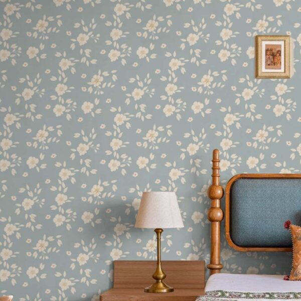 Hazel Wallpaper in Powder Blue with soft white floral pattern behind a wooden bed and bedside lamp