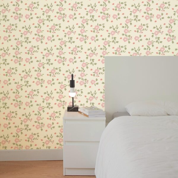 Hazel Wallpaper in Rosewater styled in a soft bedroom with blush floral pattern and green leaves on a warm cream background