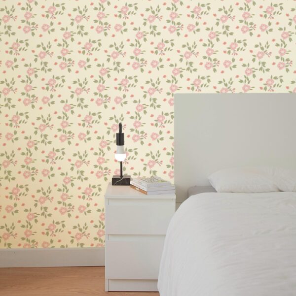 Hazel Wallpaper in Rosewater styled in a soft bedroom with blush floral pattern and green leaves on a warm cream background