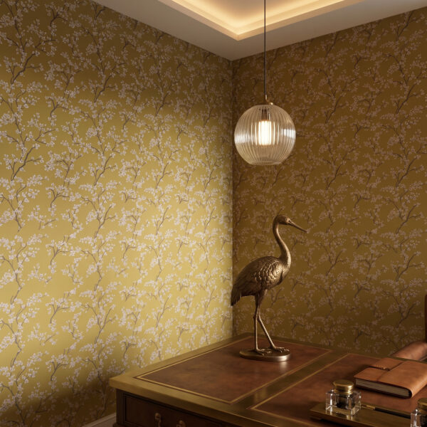 A zoomed-in of a delicate floral branches with white blossoms and dark stems on ochre wallpaper